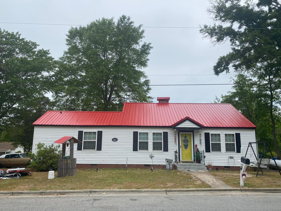 A Brite Red Metal Roof on a Home with a White Façade